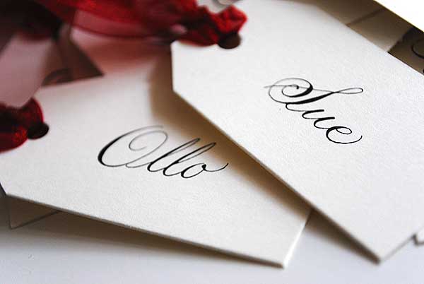 These luggage tags were handwritten for a wedding with a sheer red ribbon