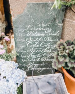 Slate order of the day sign for a Tebbey and Co wedding at Askham Hall