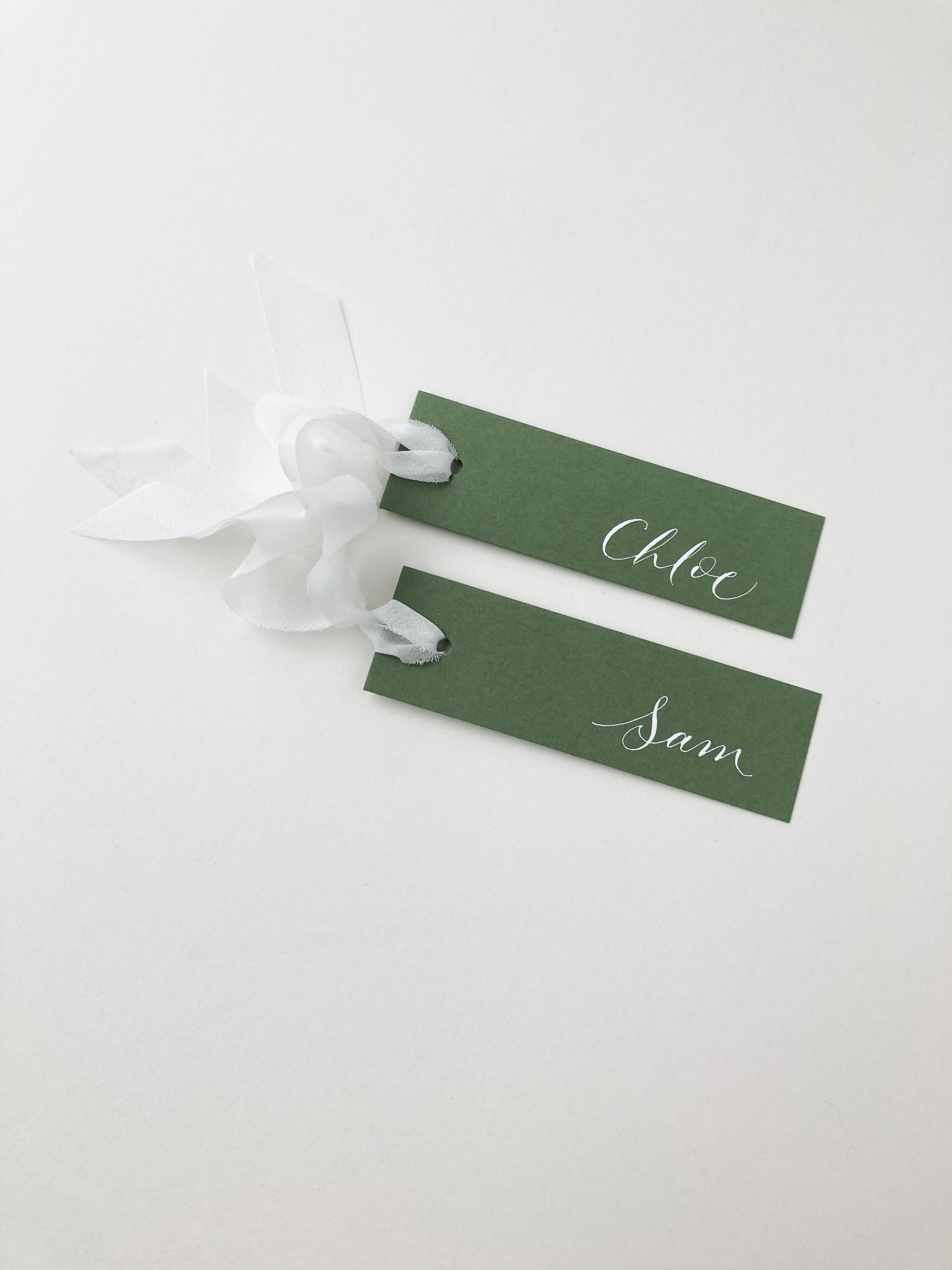Olive green place names with white calligraphy and white peace silk ribbon