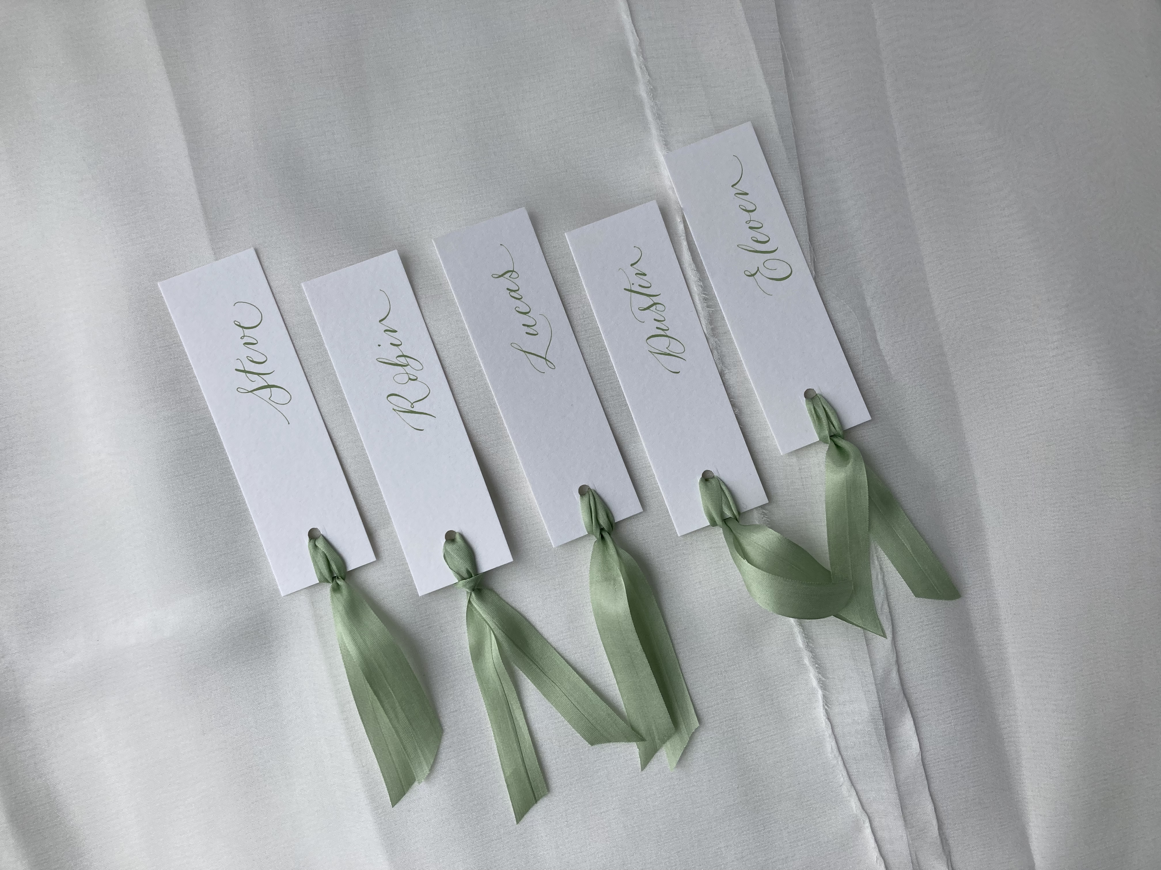 White place names with olive calligraphy and olive silk ribbon