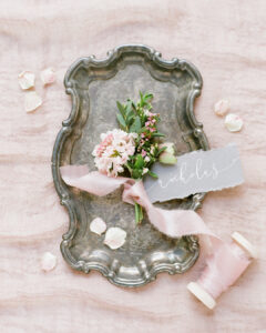 torn edge grey place name and a floral buttonhole on a silver tray