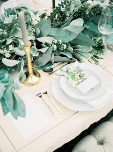 Wedding tables filled with foliage and a place setting with calligraphy name card