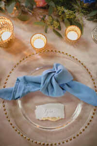 Wedding place setting with soft blue napkin and torn edge calligraphy place name card