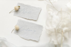 Delicate modern calligraphy place names with flower buds and silk in the background