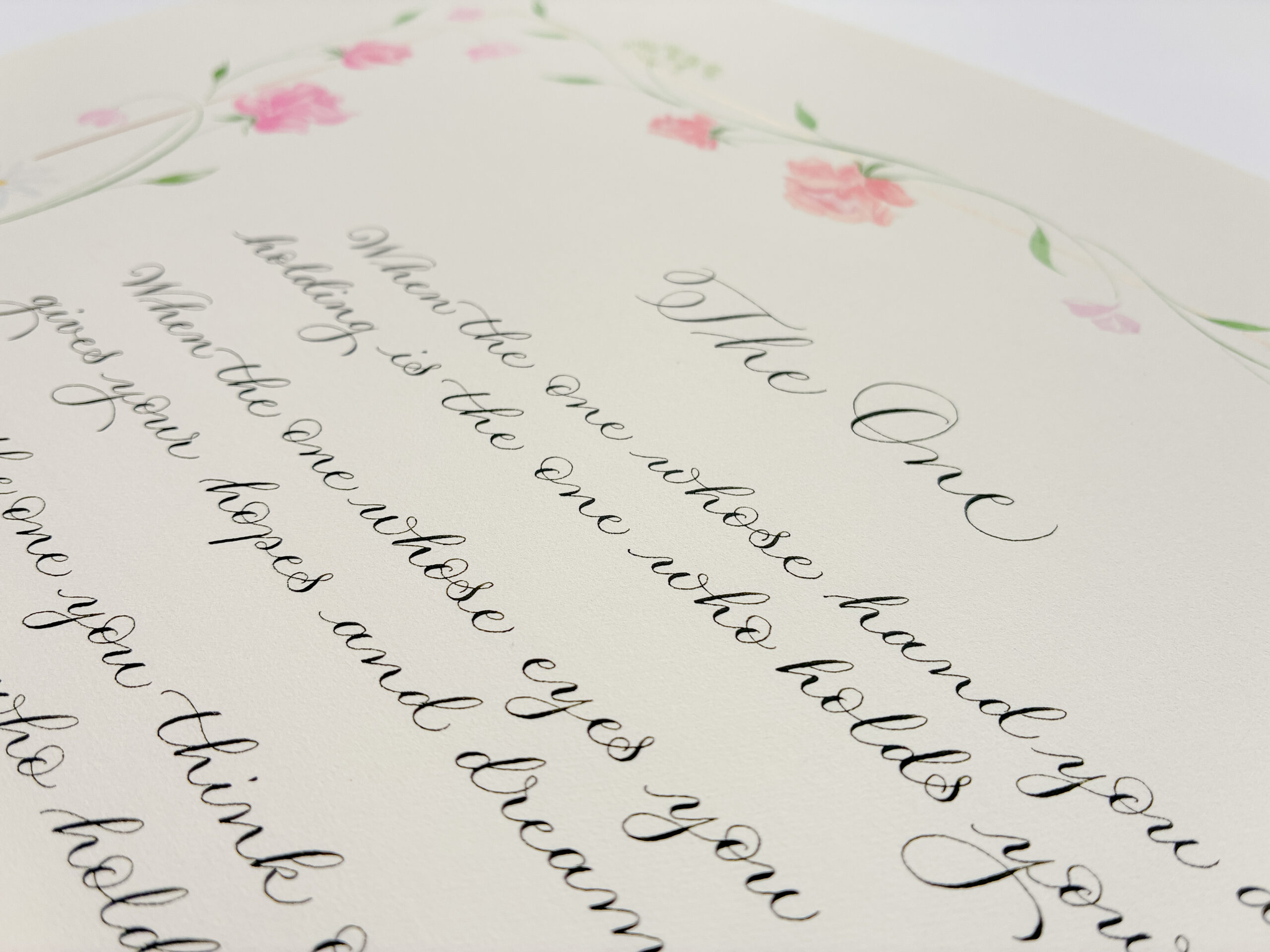 Top of a calligraphy poem showing title 'The One' and part of the first lines, with soft pink rose illustrations around the edge