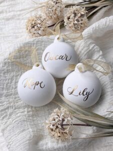 Three white baubles with gold names on